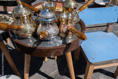 A few ornamented turkish coffee turk or cezve displayed at flea market © vadiml