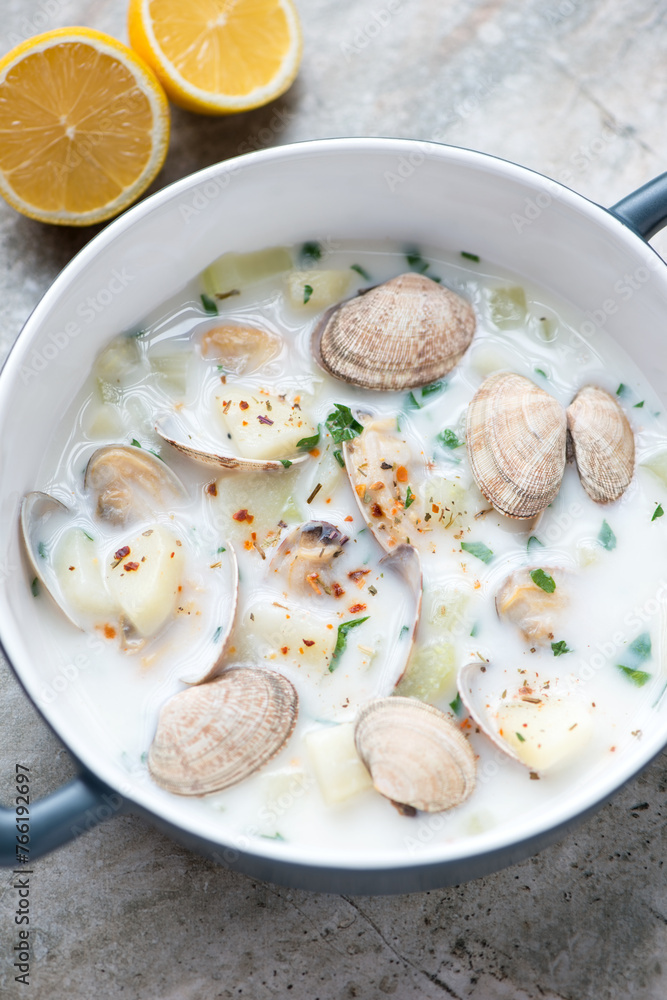 New England chowder with littleneck clams in a grey serving pan, vertical shot, middle closeup, selective focus