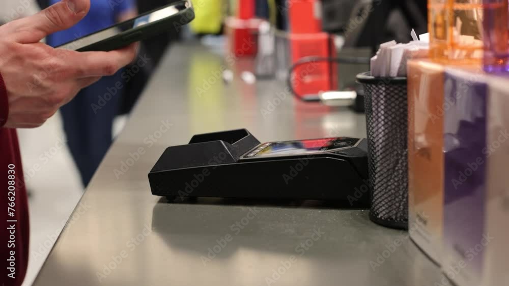 Contactless Payment in Store with Smartphone. Modern payment method captured as a man completes a transaction by tapping his smartphone to the terminal in a retail store. Contactless Payment in Store with Smartphone. Modern payment method captured as a man completes a transaction by tapping his smartphone to the terminal in a retail store.