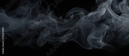 Smoke is billowing and swirling in the air against a black background, creating a mysterious and atmospheric effect