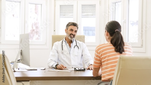 Happy male doctor talking to female patient in clinic