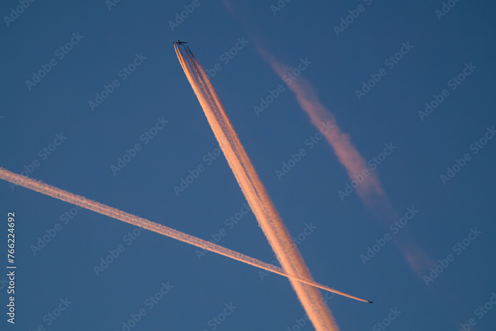 spring morning with a clear blue sky and two airplanes with orange vapor trails spring morning with a clear blue sky and two airplanes with orange vapor trails