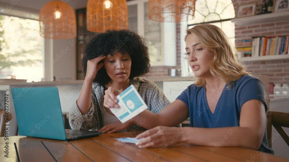 Couple with laptop at home sitting at table worried about debt how to pay bills and rising cost of living - shot in slow motion Couple with laptop at home sitting at table worried about debt how to pay bills and rising cost of living - shot in slow motion