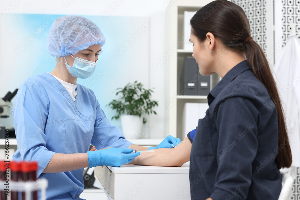Fototapeta premium Laboratory testing. Doctor taking blood sample from patient at white table in hospital