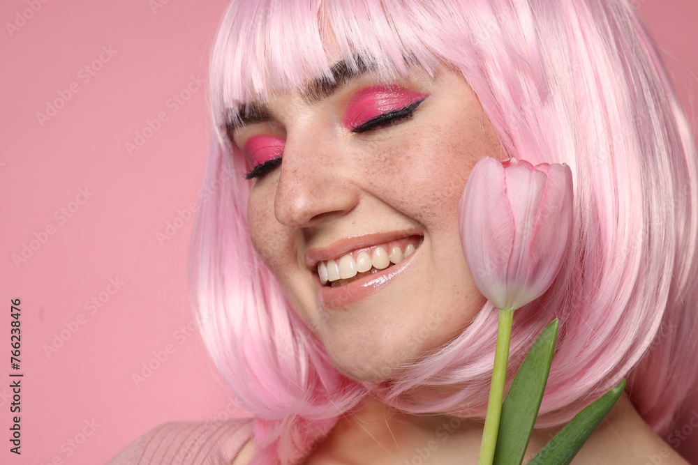 Smiling woman with bright makeup, fake freckles and tulip on pink background, closeup Smiling woman with bright makeup, fake freckles and tulip on pink background, closeup