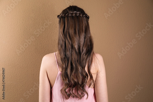 Woman with braided hair on light brown background, back view