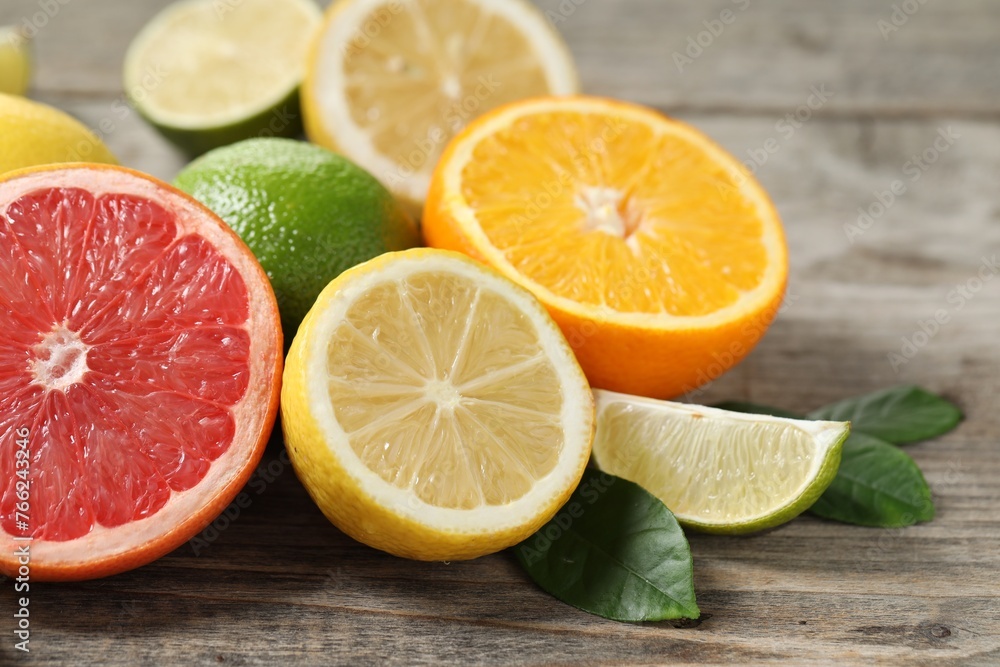 Different fresh citrus fruits and leaves on wooden table, closeup Different fresh citrus fruits and leaves on wooden table, closeup