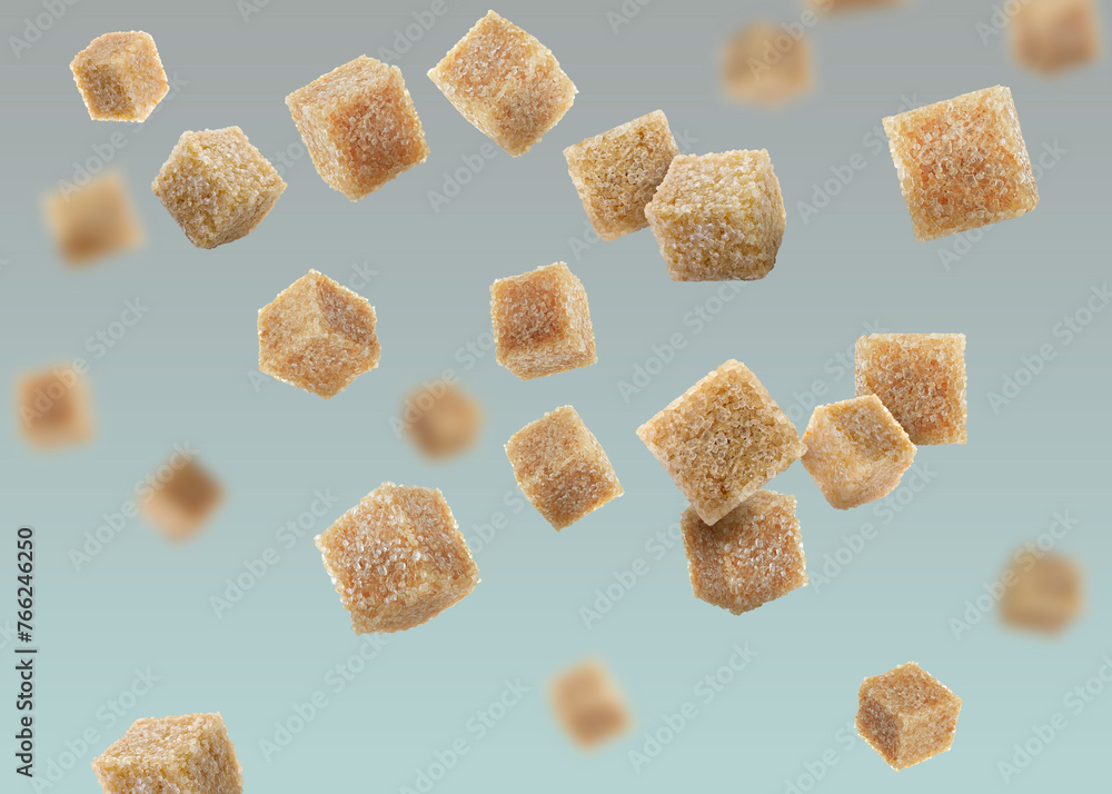 Brown cane sugar cubes falling on color gradient background Brown cane sugar cubes falling on color gradient background