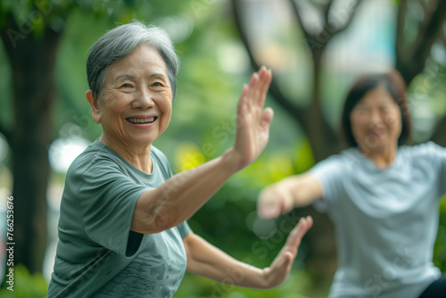 Two senior women practicing Tai Chi together in the sunlight at the park, smiling and doing Tai Chi or yoga poses in a park. enjoying their time together and engaging in a healthy activity