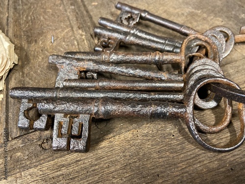 A bunch of antique  17th and 18th century keys from an old English country house laying on an old oak table.  photo