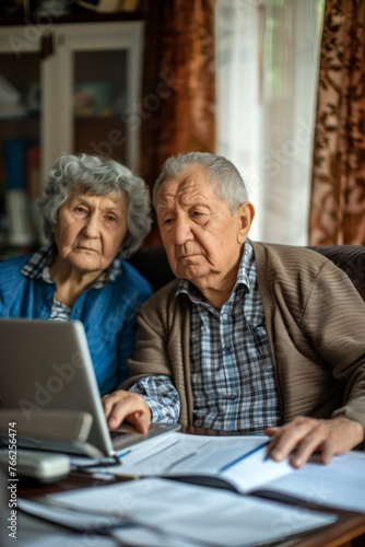 Elderly couple, old lady and man sitting together with a laptop and documents, discussing pension retirement plans, insurance, financial planning or vacation for seniors.  © Ilia