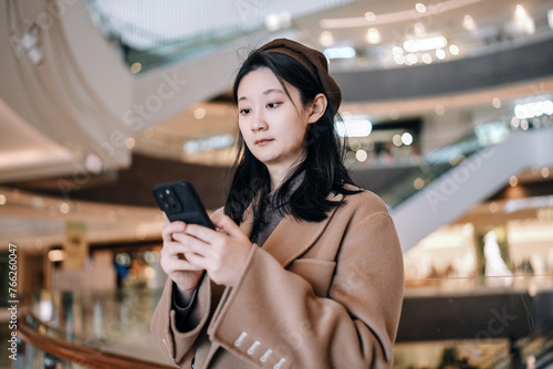 Young Stylish Woman Using Smartphone in Shopping Mall