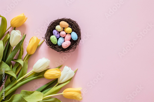 Easter card with eggs in the nest and tulips, on a pink background, copy space