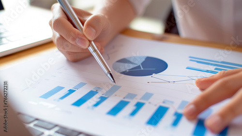Financial overview of the hand pointing at a presentation chart on paper with colorful graphs and charts