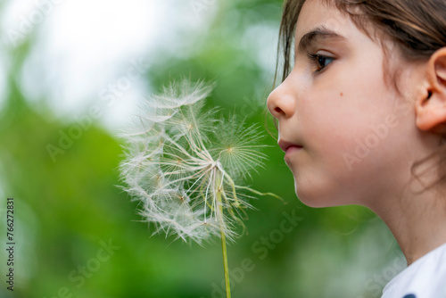 Little girl blowing dandelion seeds