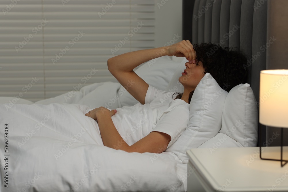 Young woman suffering from headache in bed at night Young woman suffering from headache in bed at night