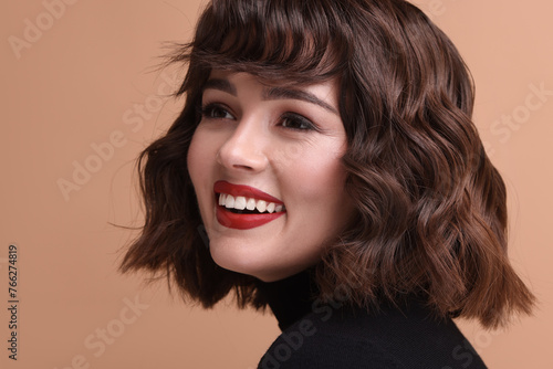 Portrait of beautiful young woman with wavy hairstyle on beige background
