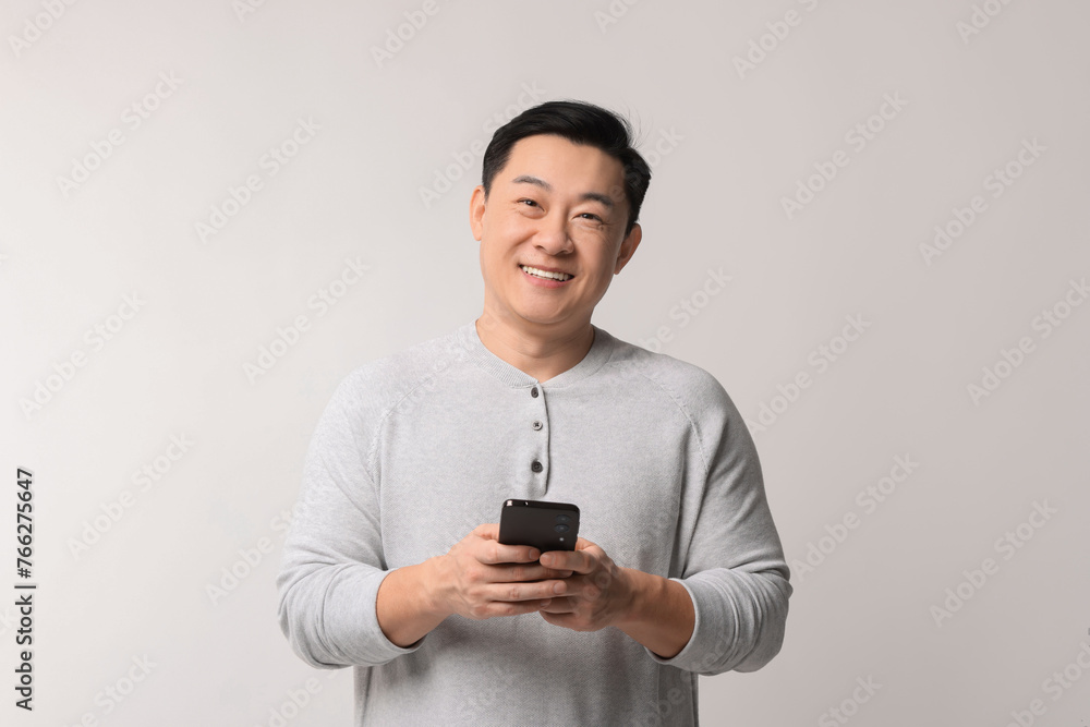 Portrait of happy man with smartphone on light background Portrait of happy man with smartphone on light background