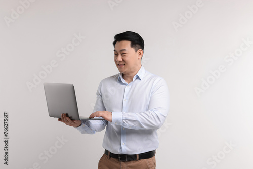 Portrait of happy man with laptop on light background