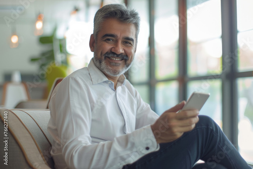 Charismatic gentleman with a silver beard cheerfully using his smartphone.