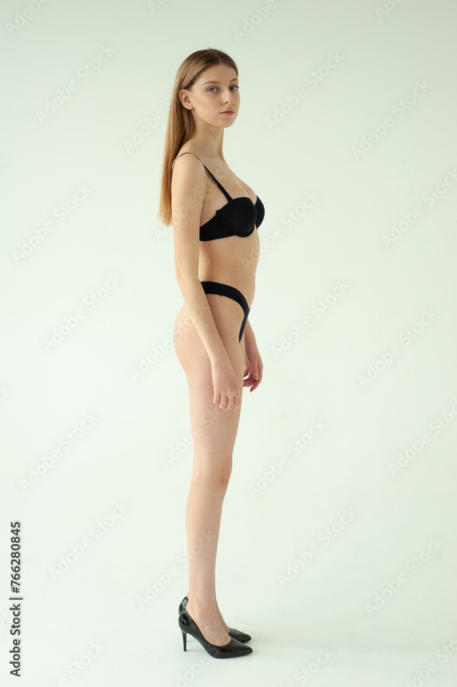 Snap Models. Full length portrait of a beautiful young woman in black bikini isolated on white background