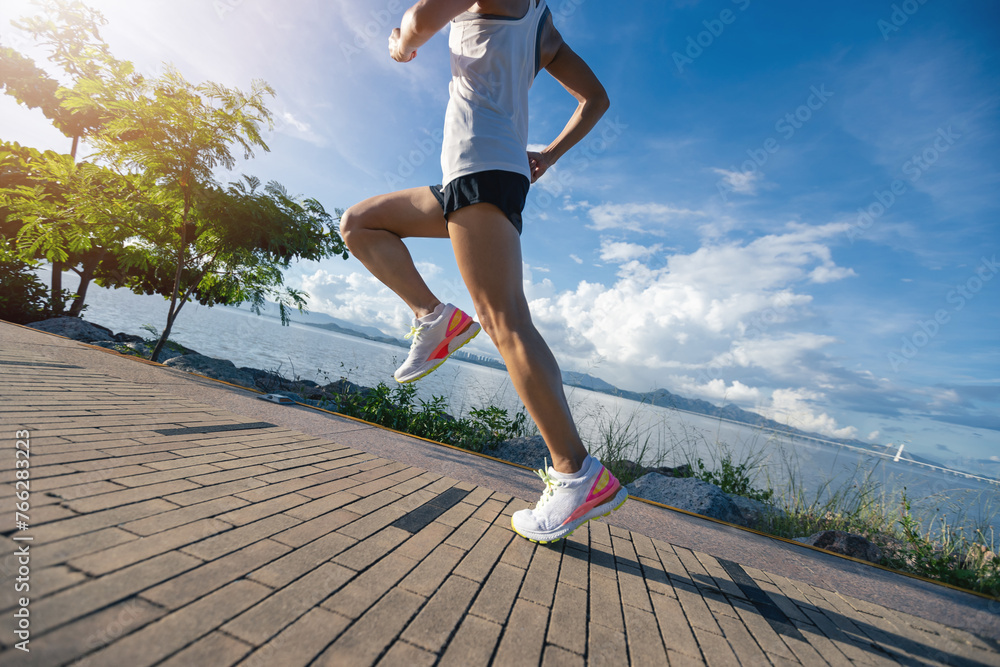 Fitness woman running on sunny tropical seaside