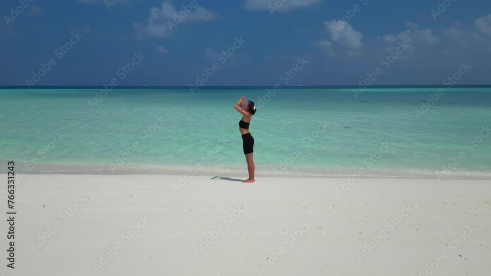 woman doing yoga practice for breathing and calming on Maldives beach aeiral view woman doing yoga practice for breathing and calming on Maldives beach aeiral view