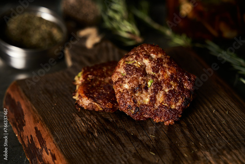 Beef, zucchini and cheddar cheese patties or cutlets on wood board. Low key food photo, dark background. Dinner meat concept, full of proteins.