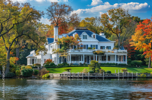 Photo of large white colonial style house with blue accents, single roof on the shore in Long Island New York overlooking beautiful lake