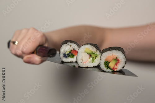 Kawałki rolek sushi na japońskim nożu.