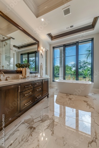 Large master bathroom features marble tile walkin shower freestanding tub and double vanity topped with white quartzite underlit cabinets. view deck looks over yard.