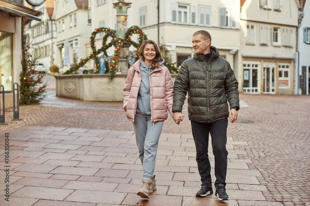 Loving couple of tourists walking around old town. Couple of lovers leisurely stroll in the cool autumn morning on the streets of a BIETIGHEIM-BISSINGEN (Germany). The guy holds his wife. Vacation