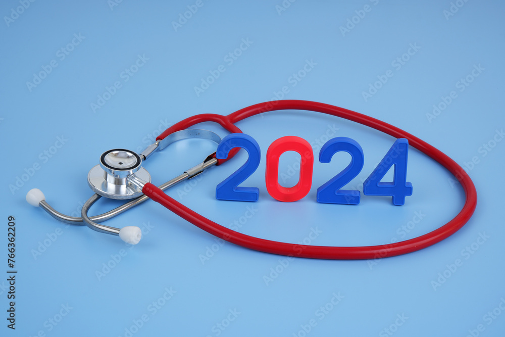 Red stethoscope and numbers 2024 on blue background. Medicine and healthcare in year 2024.