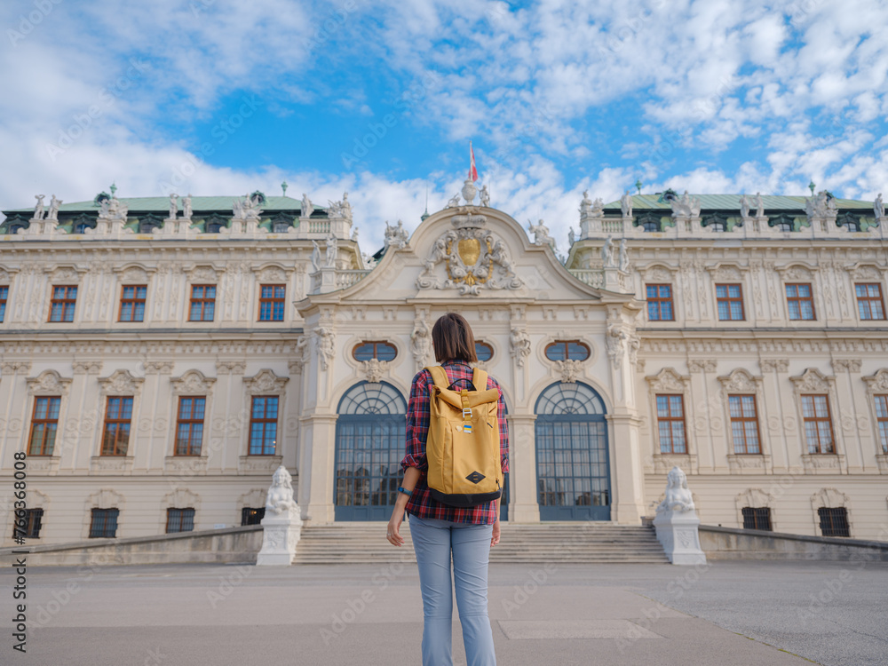 Female tourist traveling in Austria, capital city Vienna. summer female solo trip to Europe, happy young woman walking in park near Belvedere palace complex in Baroque style.