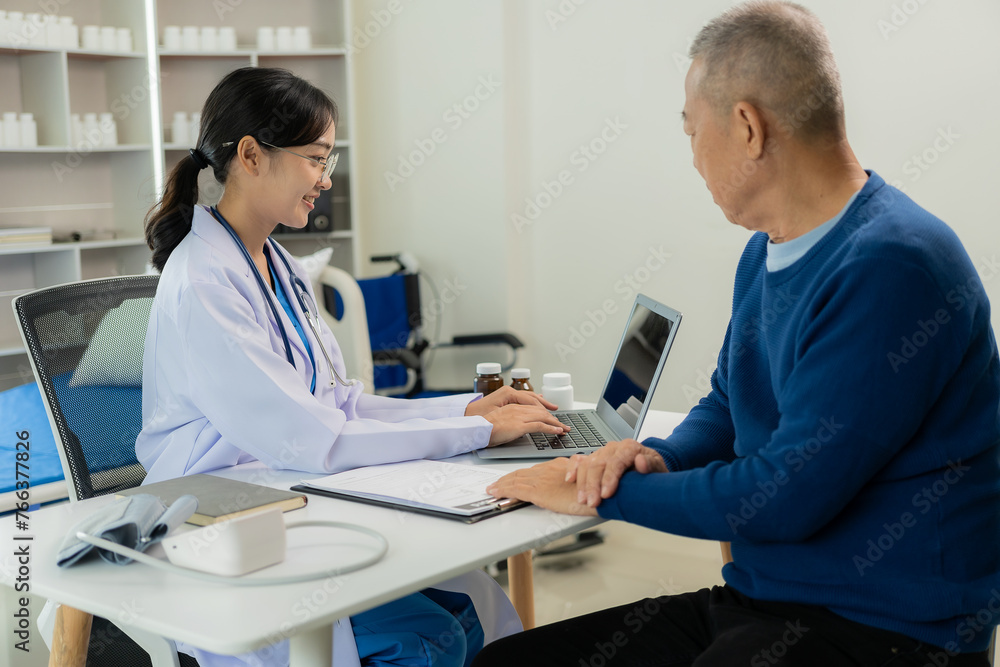 Fototapeta premium Asian professional female doctor talking with male patient about his pain and symptoms while giving consultation at table in examination room at health care hospital