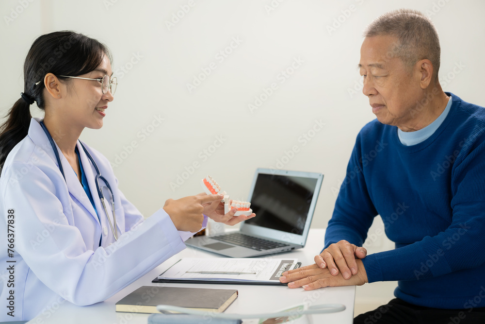 Image of a doctor or dentist presenting a tooth model, advising the patient on dental treatment and dentistry. Woman shows dentures to a male patient and explains dental treatment for the patient. Image of a doctor or dentist presenting a tooth model, advising the patient on dental treatment and dentistry. Woman shows dentures to a male patient and explains dental treatment for the patient.