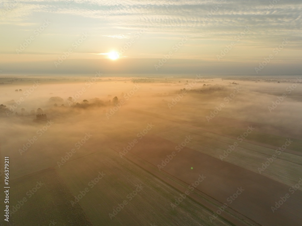 Brzask na wsi z lotu ptaka, ujęcia z drona wsi o brzasku, wschód słońca na wsi, pusząca się o poranku wieś, pola owite mgłą o brzasku, poranek we mgle
