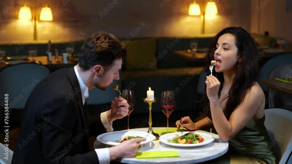 Happy man and woman having romantic dinner in the restaurant while eating salads and toasting with wine. Lifestyle, love, relationships concept. Slow motion Happy man and woman having romantic dinner in the restaurant while eating salads and toasting with wine. Lifestyle, love, relationships concept. Slow motion