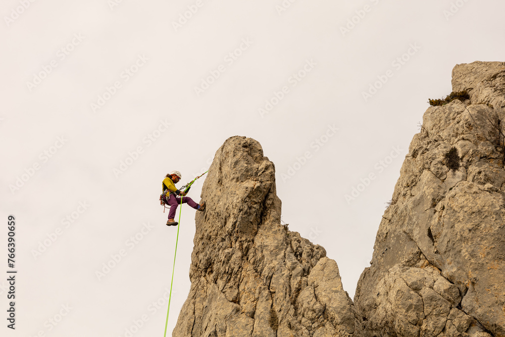 A man is climbing a rock face with a yellow rope. Concept of adventure and excitement, as the man is taking on a challenging and potentially dangerous activity