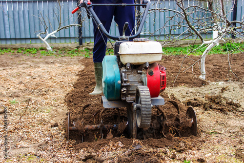 a male farmer works in the field on a walk behind a walk-behind tractor, plows the land with a plow