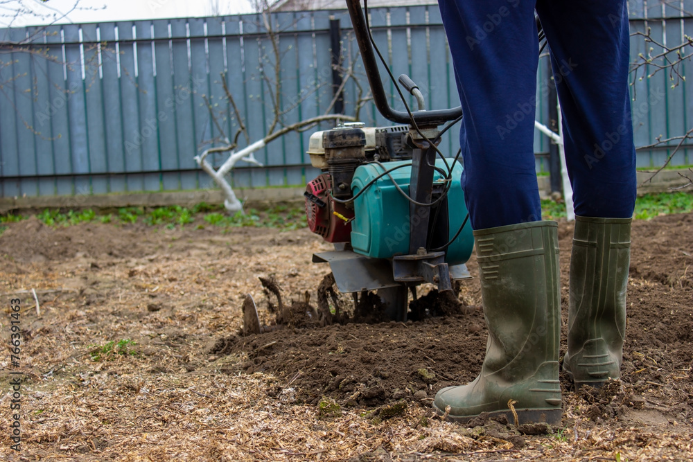 a male farmer works in the field on a walk behind a walk-behind tractor, plows the land with a plow a male farmer works in the field on a walk behind a walk-behind tractor, plows the land with a plow