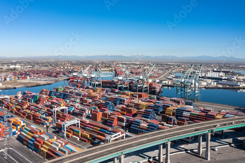 Aerial view of the Vincent Thomas Bridge. Port with cranes and several colorful containers. Sunny day. San Pedro, CA, USA
