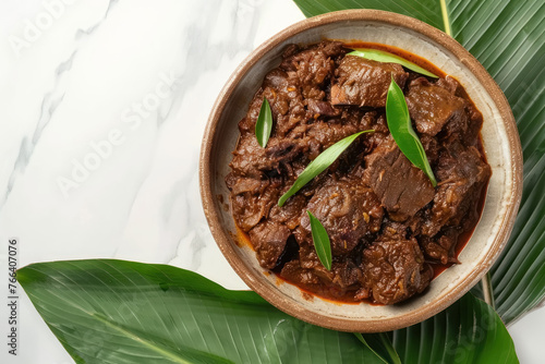 indonesian rendang dish with tender coconut beef on a leafy background photo