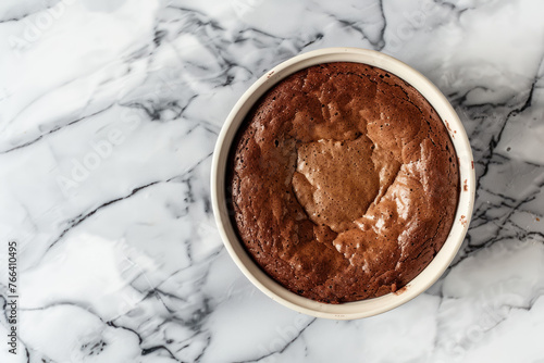 classic chocolate soufflé in white ramekin on marble background top view