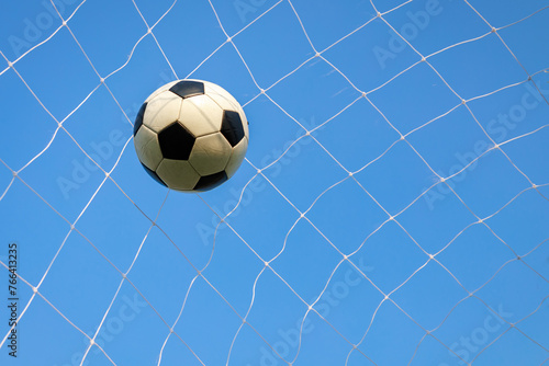 Soccer ball in a goal net under blue sky. Sport exercise of football team concept with copy space.