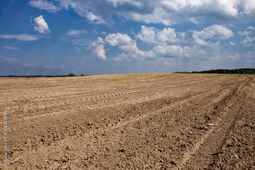 Clouds hover over a large expanse of tilled soil. Clouds hover over a large expanse of tilled soil.