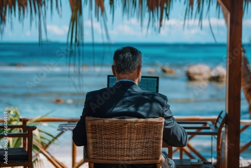 Mature businessman in suit working on computer on the beach. Freelance online remote work