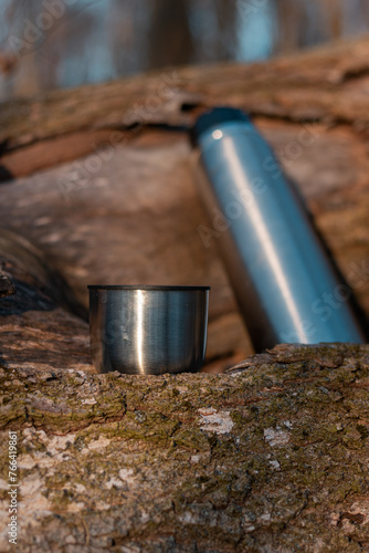 a thermos of coffee in the forest. spring landscape in the forest. a cup of tea in the forest. hot time with a thermos in the forest. hot coffee from a thermos in the forest. thermos of hot drink