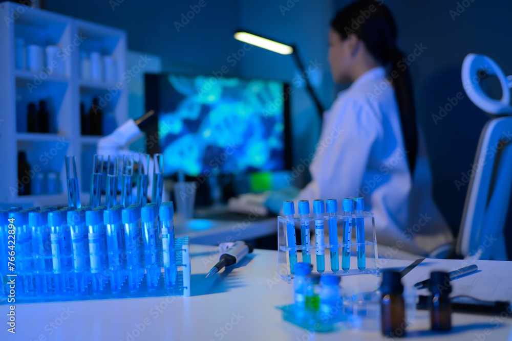 A woman in a white lab coat is working on a computer in a lab A woman in a white lab coat is working on a computer in a lab