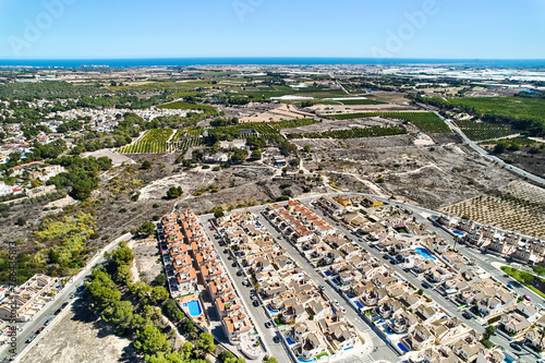 Drone point of view countryside meadows and Pinar de Campoverde residential district view with modern new-built houses, villas view from above. Summer day. Costa Blanca, Province of Alicante, Spain
 photo